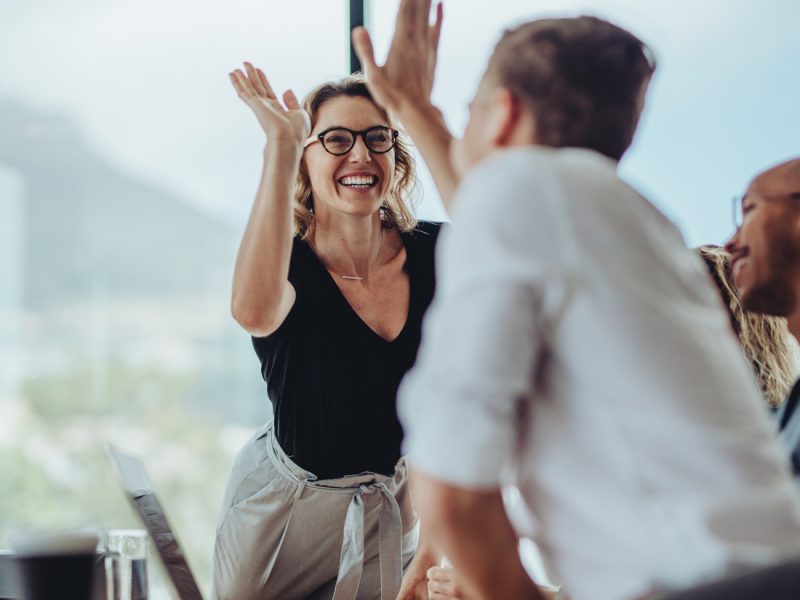 Happy executive woman giving a high five in an office after a successful job interview