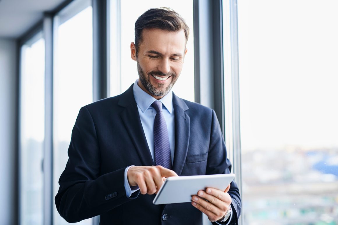 Confident executive reviewing career options on a digital tablet 
