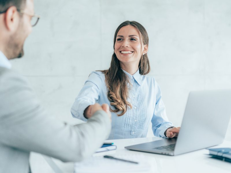 Smiling executive woman shaking hands during a successful job offer negotiation in a modern office