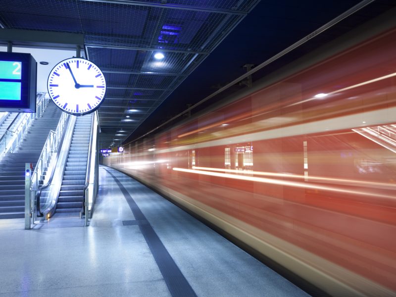 Blurry train speeding past a station clock, symbolizing the urgency of resume reviews in executive hiring.